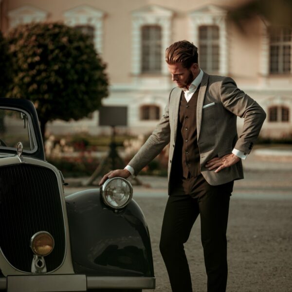Confident wealthy young man near classic convertible.
