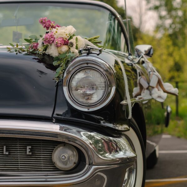 A vintage car parked with flowers on the side of the street