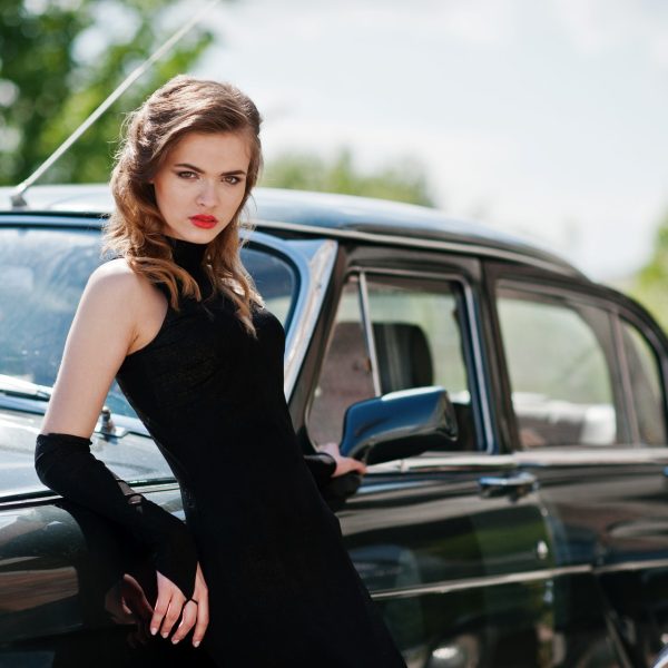Portrait of beautiful fashion girl model with bright makeup in retro style leaned on a vintage car